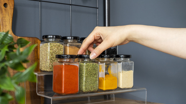 Hand choosing a jar from a spice rack