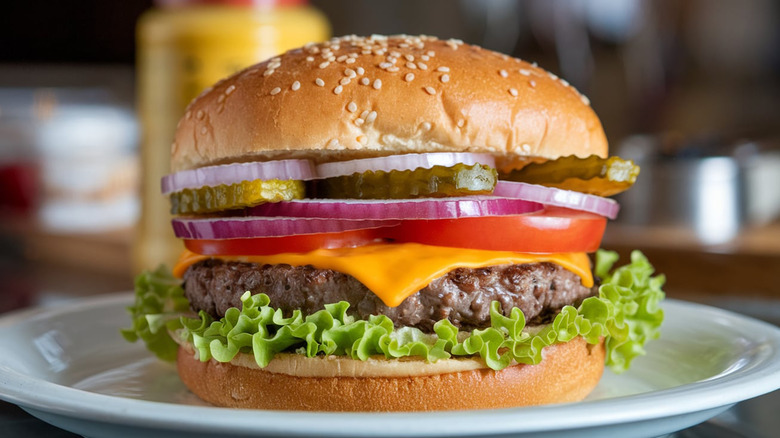 A classic cheeseburger with lettuce, and sliced tomatoes, pickles, and red onions.
