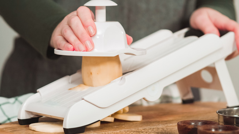 Person slicing potato with mandoline