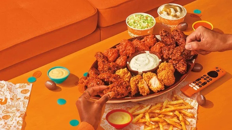 An assorted plate of Popeye's wings on a football platter with side dishes