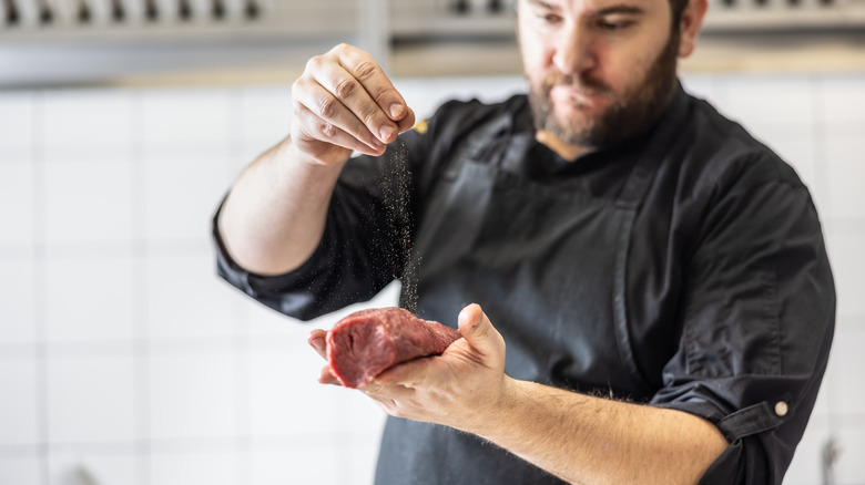 Chef seasoning beef by hand