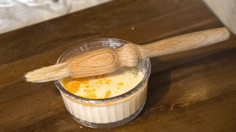Pastry brush with egg wash on wooden table