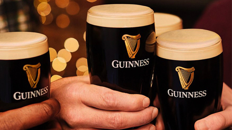 hands holding pints of Guinness