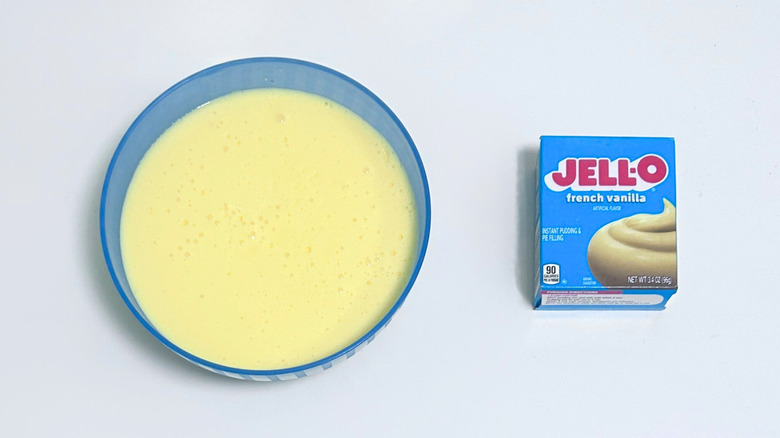 A bowl of pale yellow pudding next to a box of Jell-O French Vanilla Pudding Mix