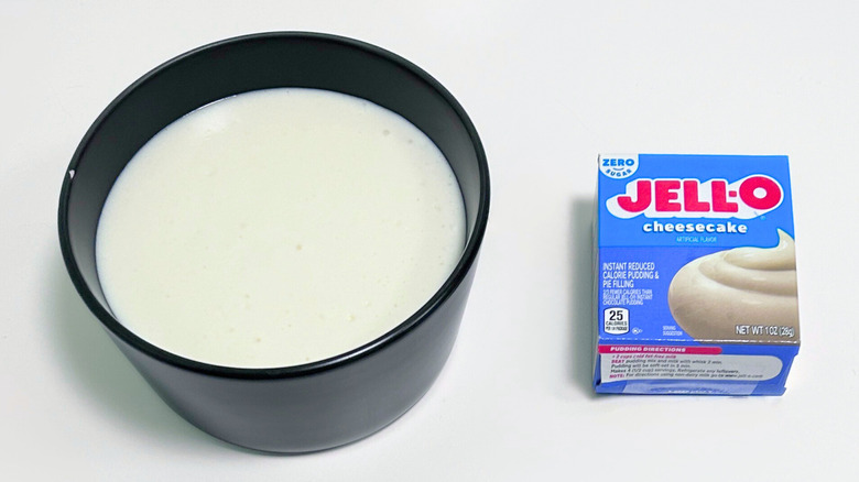 A bowl of off-white pudding next to a box of Jell-O Zero Sugar Cheesecake Pudding Mix