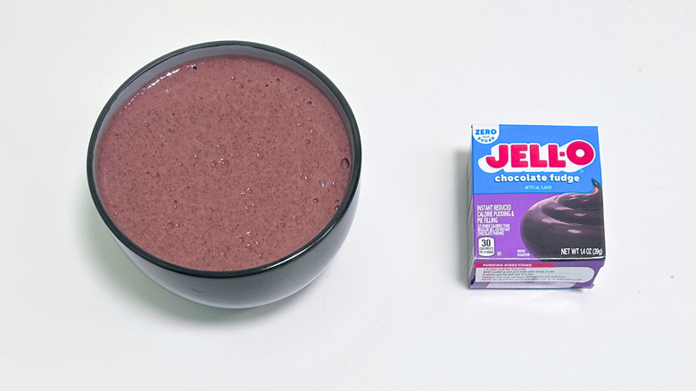A bowl of bubbly looking brown pudding next to a box of Jell-O Zero Sugar Chocolate Fudge Pudding Mix