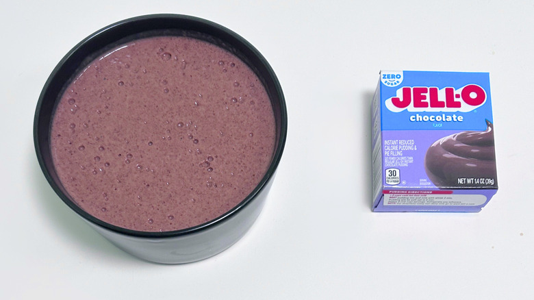A bowl of bubbly chocolate brown pudding next to a box of Jell-O Zero Sugar Chocolate Pudding Mix