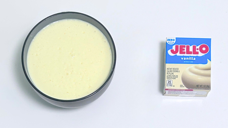A bowl of pale yellow pudding next to a box of Jell-O Zero Sugar Vanilla Pudding Mix