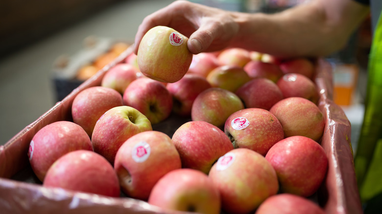 hand removing apple from crate