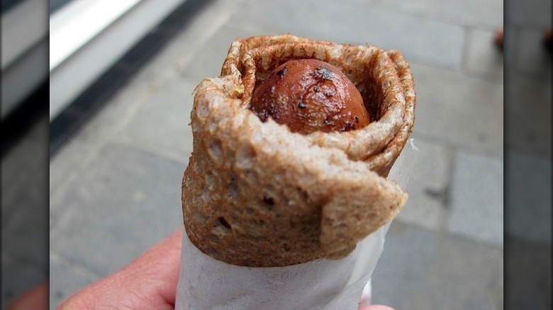 Person holding galette saucisse 