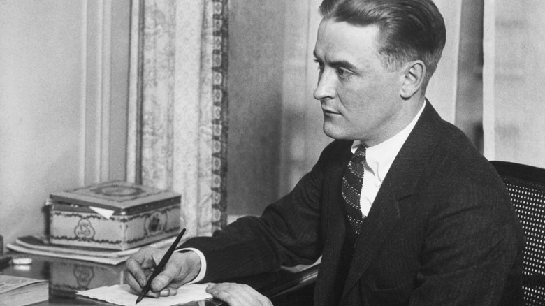 Photo of F. Scott Fitzgerald posed with pen and paper at his desk