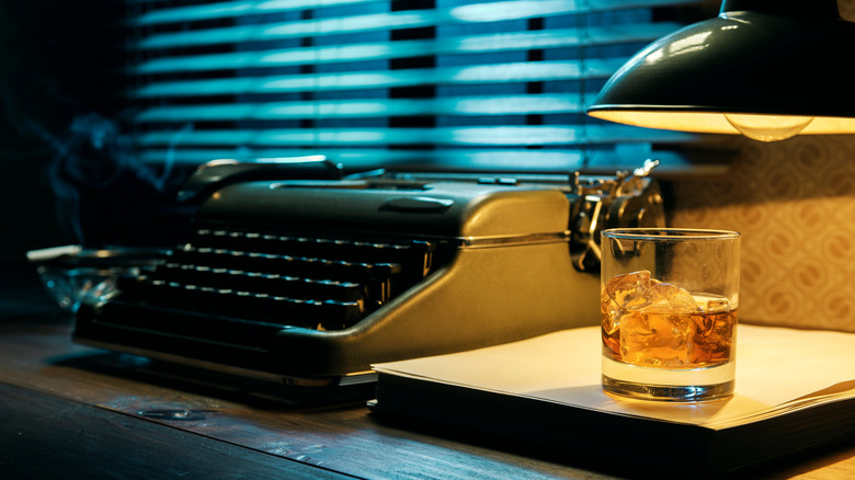 Typewriter and whiskey glass positioned on desktop