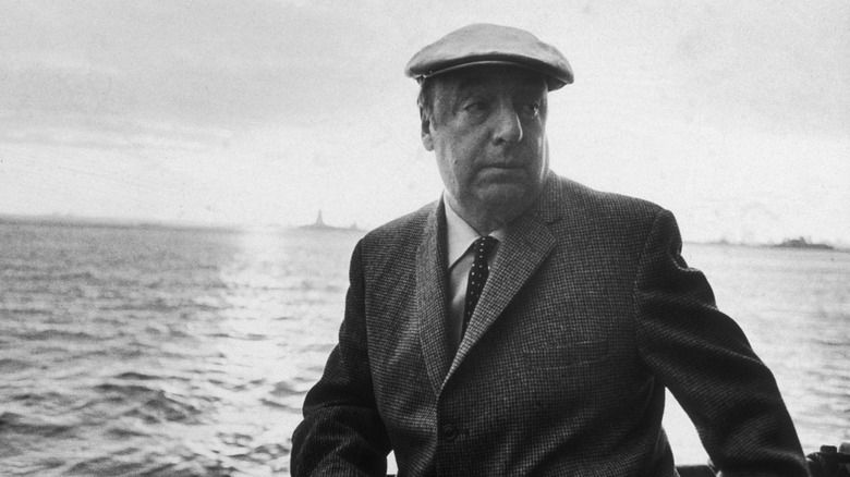Photo of Pablo Neruda leaning on railing on board a ship