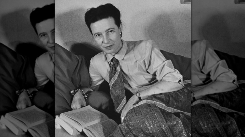 Photo of Simone de Beauvoir with open books on a sofa