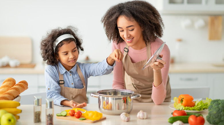 mother and daughter salting pot of water