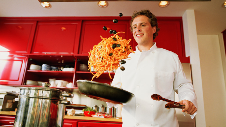 man tossing pan of food
