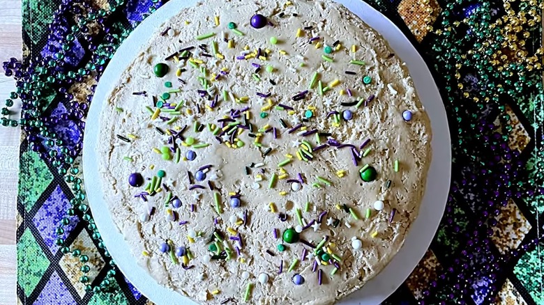 Whole Gâteau de Sirop or syrup cake garnished with colorful sprinkles and surrounded with Mardi Gras beads