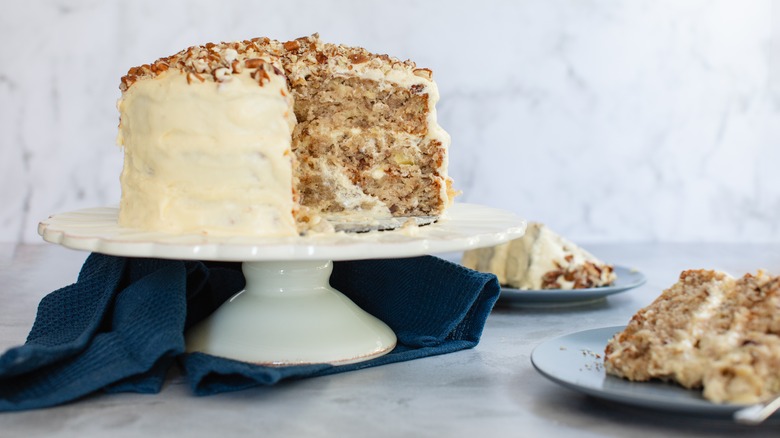 Three-tier hummingbird cake on cake stand with slice cut out of it
