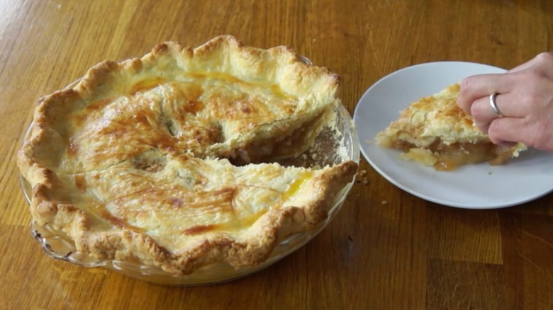 Person serving a slice of mock apple pie onto a white plate