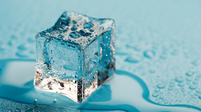 Melting ice cube on blue background