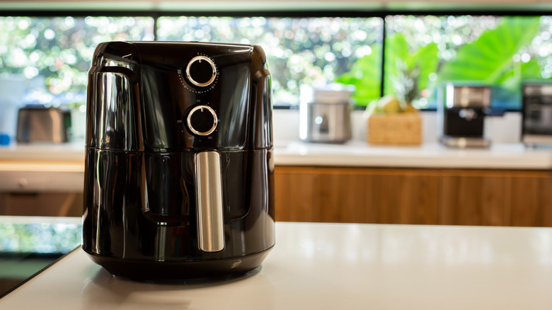 Black air fryer sitting on kitchen countertop
