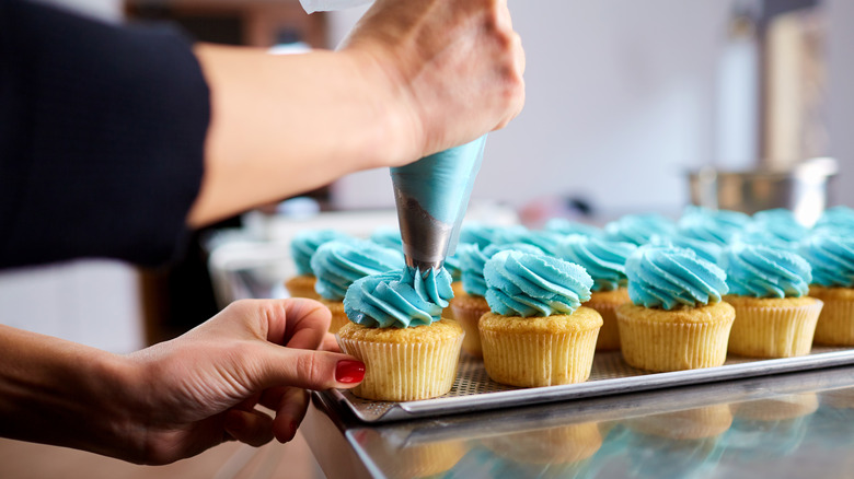 piping blue icing on cupcakes