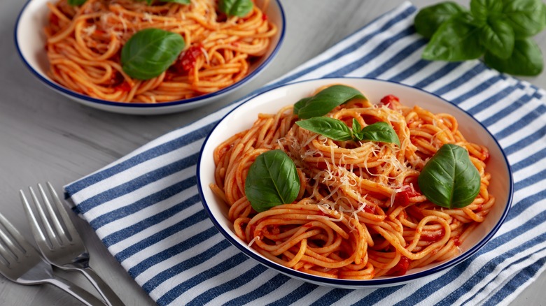 Two bowls of homemade pasta pomodoro garnished with fresh basil