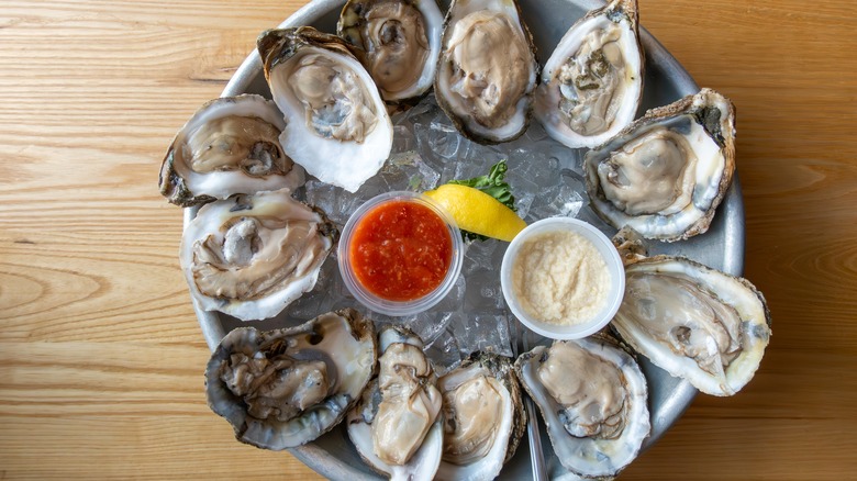 Platter of oysters on the half shell over ice served with cocktail sauce and mayonnaise
