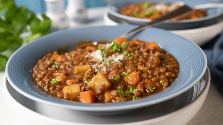 a bowl of lentil and carrot stew garnished with parsley and grated cheese