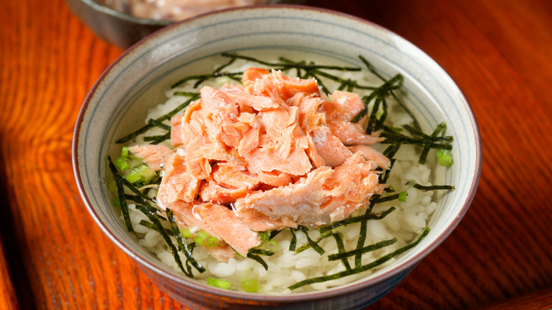 a bowl of ochazuke topped with strips of seaweed and salmon