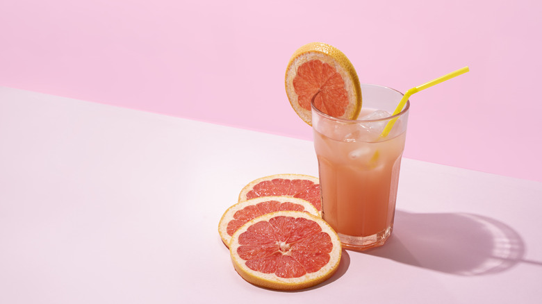 Glass of ruby red grapefruit juice and sliced grapefruit