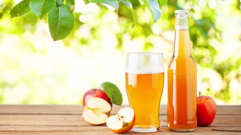 Hard apple cider in a bottle and poured into a glass