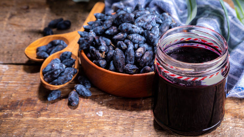 Bowl of blue haskap berries next to a jar of haskap berry jam