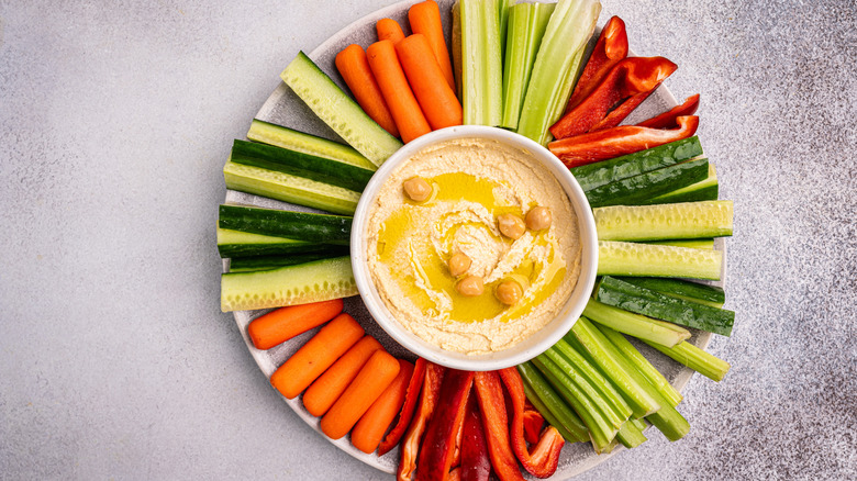 Bowl of hummus surrounded by vegetables