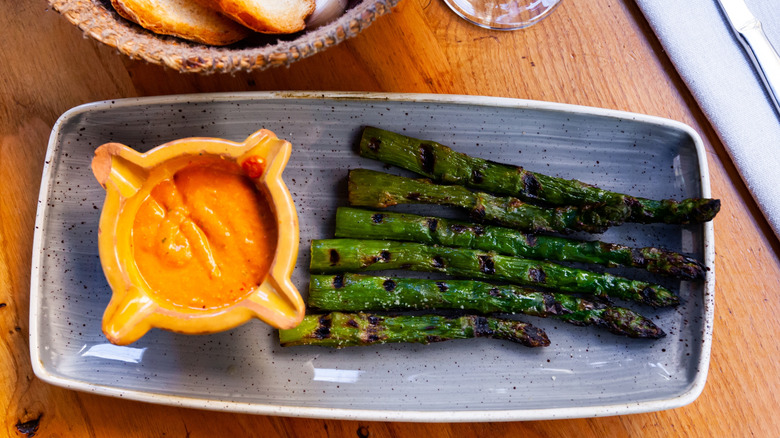 Square blue plate of grilled asparagus with Romesco