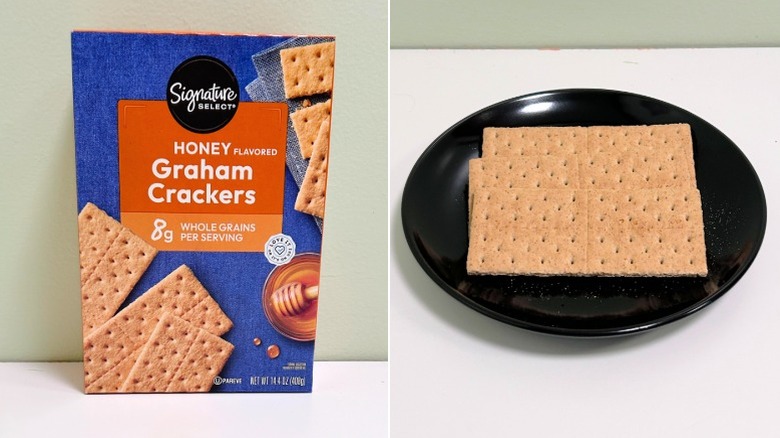 A box of Signature Select Honey Graham Crackers next to a black plate of graham crackers