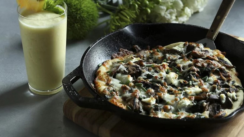 White Pizza With Mushrooms And Garlicky Greens in cast iron pan with a green smoothie