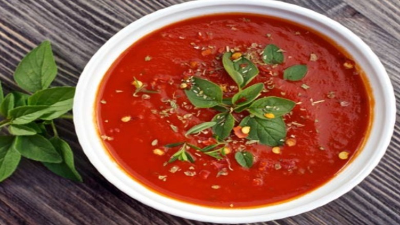 White bowl of Italian Tomato Sauce garnished with basil