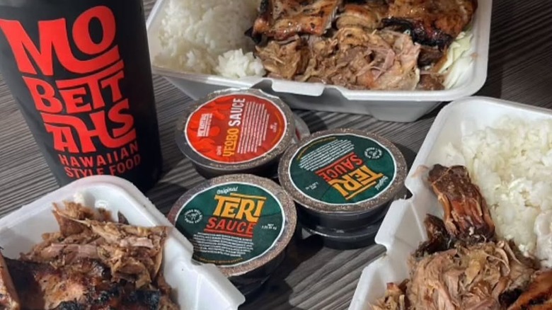 Three servings of kālua pig with rice, with sauces and a Mo'Bettah's drink cup.