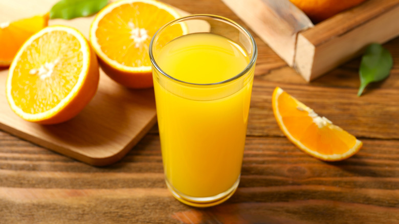 Freshly squeezed orange juice on a table with oranges