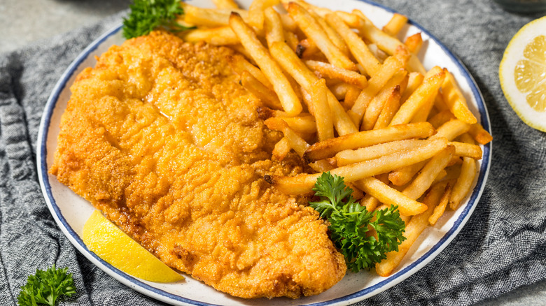 Fried catfish with fries and greenery on a white and blue plate