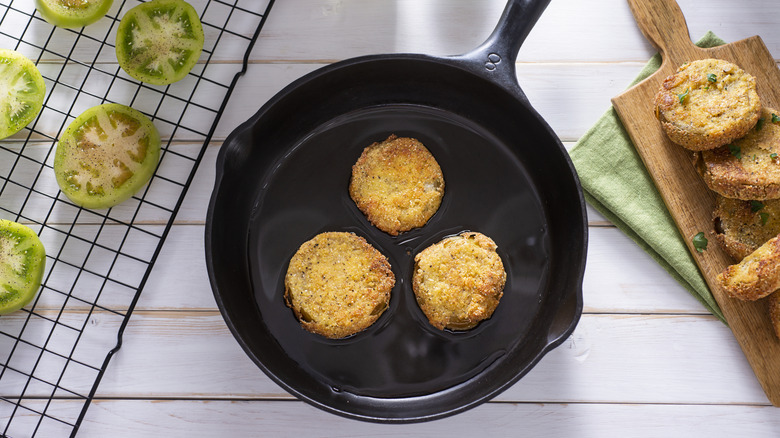 Fried green tomatoes in a black cast iron skillet of oil