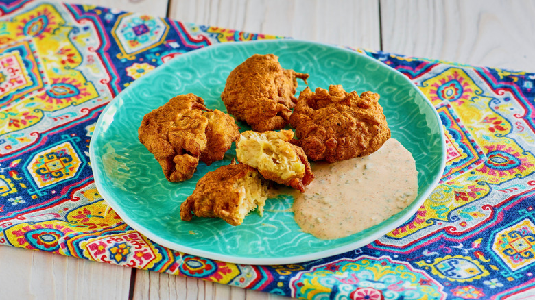 Conch fritters on an aqua plate on a colorful tablecloth