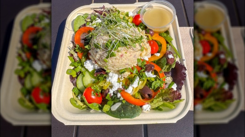 Tarpon Springs Greek Salad in a white container against a wooden surface