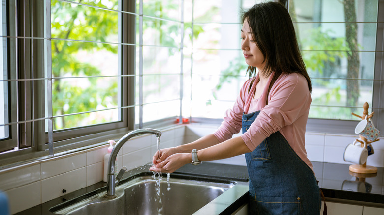 woman washing hands in kitchen