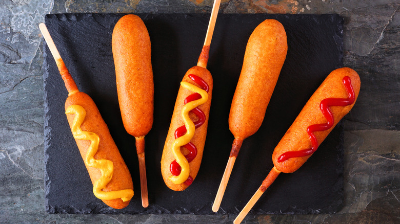 Corn dogs topped with mustard and ketchup