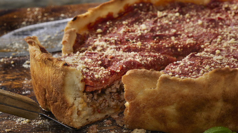 A deep dish pizza with a slice being taken out of it