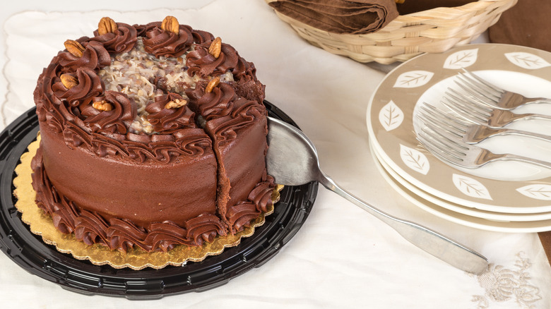 A coconut and pecan german chocolate cake being sliced, ready to serve