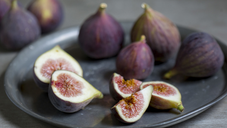 Whole and halved fresh figs on a decorative plate