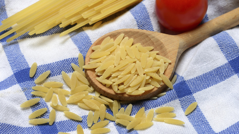 Uncooked orzo in a wooden spoon